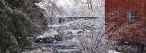 Photo of an icy waterfall beside a red barn, Norfolk, Connecticut.