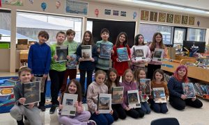 Schoolchildren holding up examples of work created using AI